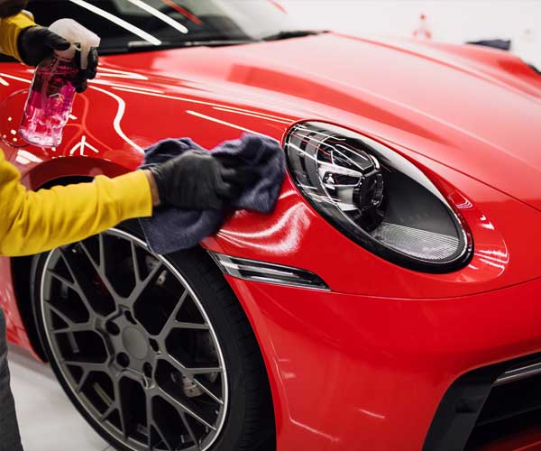 Profesional limpiando la parte delantera de un coche rojo